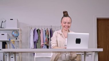 Genç anne dizüstü bilgisayarda çalışan birine gülümsüyor. Yakın çekim. 