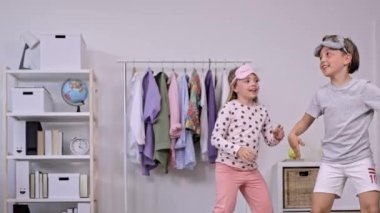 Pijama giymiş kız ve erkek kardeş birlikte dans ediyorlar. Ağır çekim. Yüksek kalite 4k görüntü