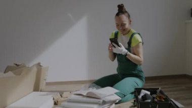Young female is assembling a piece of furniture. High quality 4k footage