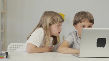 Boy of 9 years old helps his younger sister to make her homework. High quality 4k footage