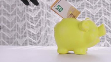 Human hand in black vinyl glove takes 50 euro banknote from piggy bank. High quality 4k footage