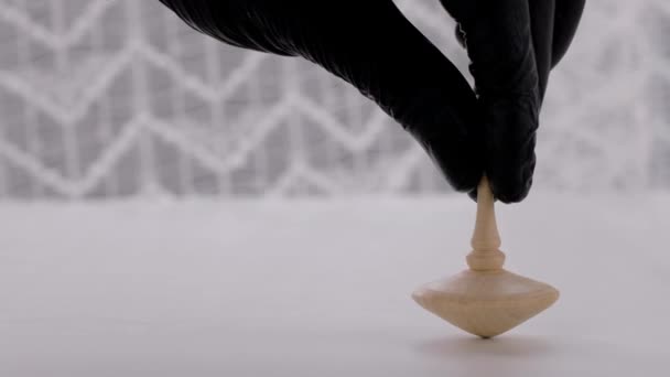 Human Hand Black Vinyl Glove Launching Wooden Spinning Top White — Stok Video