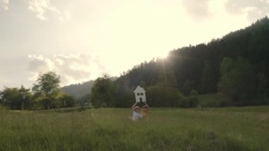 Sister and the brother are keeping paper house and mini wind turbine. Slow motion