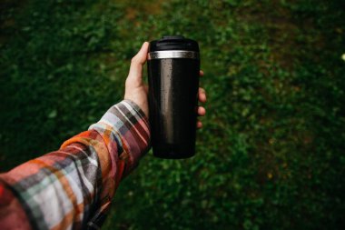 a man holds a thermos in his hand during the rain