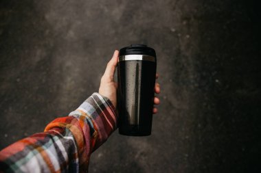 a man holds a thermos in his hand during the rain