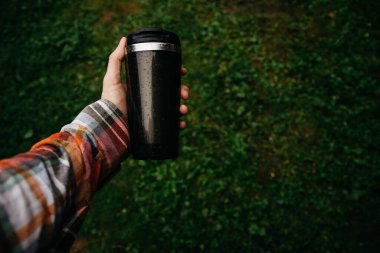 a man holds a thermos in his hand during the rain