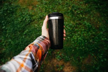 a man holds a thermos in his hand during the rain