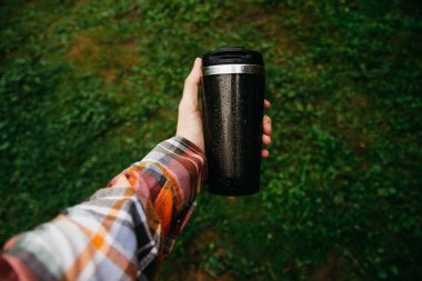 a man holds a thermos in his hand during the rain
