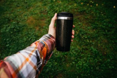 a man holds a thermos in his hand during the rain