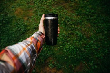 a man holds a thermos in his hand during the rain