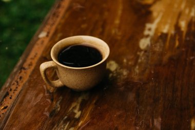 a cup of coffee stands on the table in gloomy and rainy weather.a cup of coffee in rainy weather