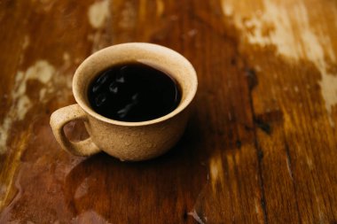 a cup of coffee stands on the table in gloomy and rainy weather.a cup of coffee in rainy weather
