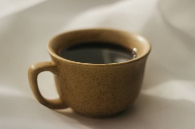 Sabahları bir fincan kahve. Espresso kahvesi. Beyaz bir bez üzerinde beyaz fincanlı kahve fincanı üzerine kahve lapası. Bir fincan kahveye güneş ışığı.