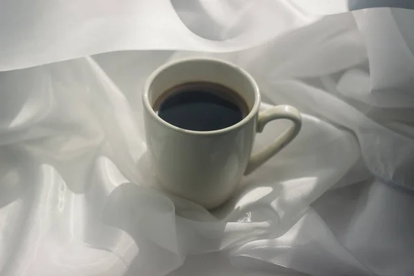 cup of coffee in the morning. espresso coffee. Coffee porridge on a white background a cup of coffee on a white cloth. sun rays on a cup of coffee