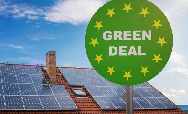 Green deal sign in front of house with photovoltaic solar panels on roof. Ecelogy concept.