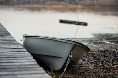 Göl kıyısındaki eski ahşap iskelede bağlı bir tekne