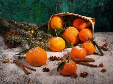 Mandalina, anason, tarçın, kozalak, top, fındık, köknar ağacı dalı ve sepetinden oluşan Noel kompozisyonu ahşap karla kaplı yüzey