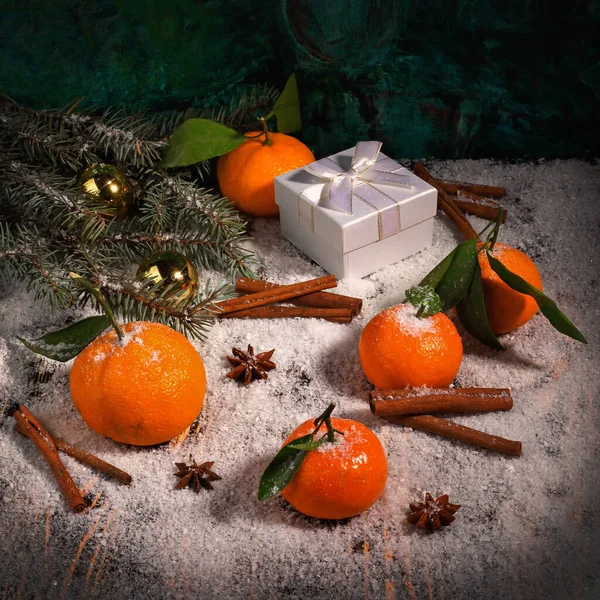 Mandalina, anason, tarçın, hediye kutusu, top ve köknar ağacının ağaç dalının Noel kompozisyonu ahşap karla kaplı yüzeyde
