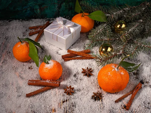Mandalina, anason, tarçın, hediye kutusu, top ve köknar ağacının ağaç dalının Noel kompozisyonu ahşap karla kaplı yüzeyde