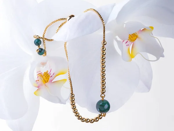 白い蘭の花に緑色のマラカイトの宝石と黄金のブレスレット — ストック写真