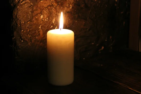 Lighted candle on a black background — Stock Photo, Image