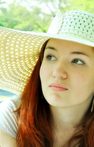 Thoughtful beautiful redheaded woman looking away in a white summer hat outdoors — Stock Photo, Image