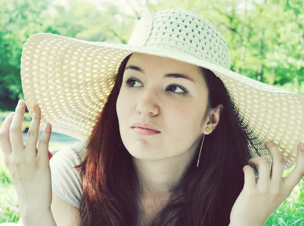 Thoughtful beautiful redheaded woman looking away in a white summer hat outdoors — Stock Photo, Image