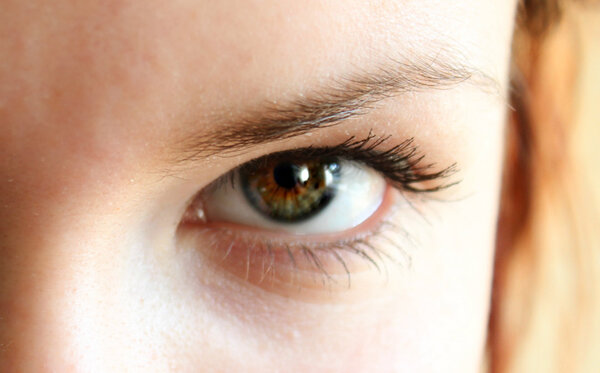 Green eye of a red-haired girl closeup