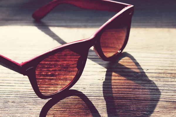 Black and red vintage sunglasses on a wooden table closeup