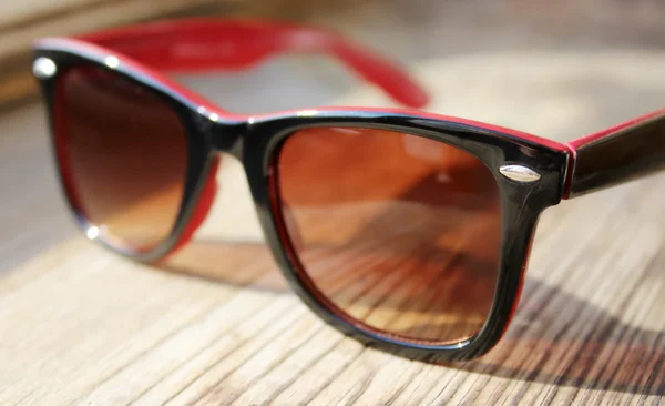 Lunettes de soleil vintage noires et rouges sur une table en bois — Photo