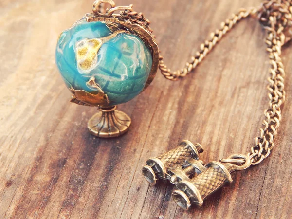 Necklace in the form of Earth globe and binoculars on a wooden background — Stock Photo, Image