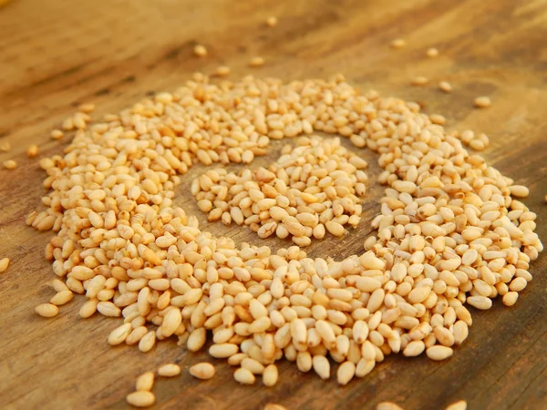 Sesame seeds in a shape of heart isolated on wooden background — Stock Photo, Image