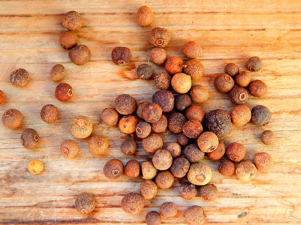 Schwarzer Piment-Pfeffer isoliert auf Holzgrund — Stockfoto