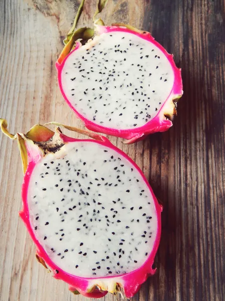 Juicy pink pitaya cut in two pieces on wooden table closeup — Stock Photo, Image