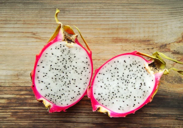 Juicy pink pitaya cut in two pieces on wooden table closeup — Stock Photo, Image