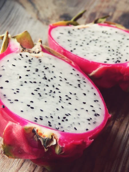 Juicy pink pitaya cut in two pieces on wooden table closeup — Stock Photo, Image