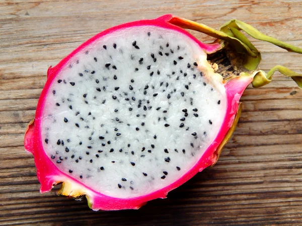 Juicy pink pitaya cut in two pieces on wooden table closeup — Stock Photo, Image