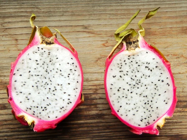 Juicy pink pitaya cut in two pieces on wooden table closeup — Stock Photo, Image