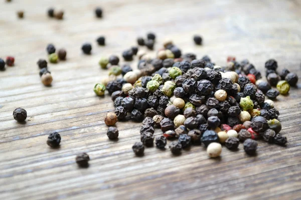 Een collectie van zwarte, rode, witte en groene peper op houten tafel — Stockfoto