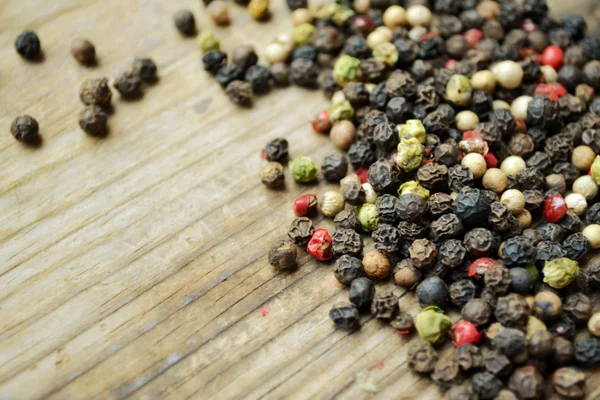 Una colección de pimienta negra, roja, blanca y verde sobre mesa de madera — Foto de Stock