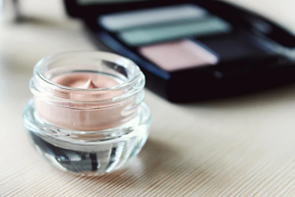 Conjunto de sombra de ojos y una imprimación de crema en un tocador —  Fotos de Stock