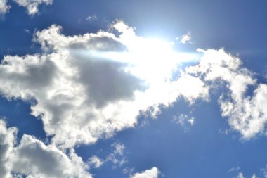 Beyaz bulutların üzerinde parlayan güneş parlak mavi gökyüzü