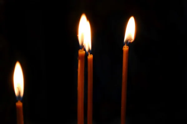 Varias velas encendidas con luz suave de su llama sobre un fondo negro —  Fotos de Stock