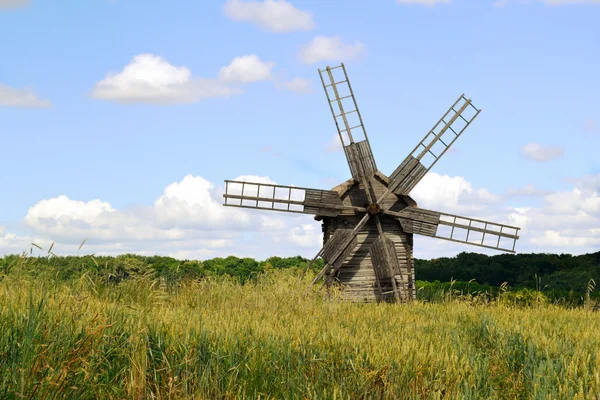 Ancien moulin à vent en bois dans un champ vert sur ciel bleu vif et nuages — Photo