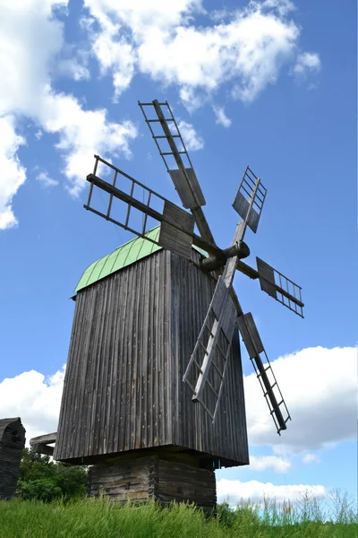 Alte hölzerne Windmühle im grünen Feld über strahlend blauem Himmel und Wolken — Stockfoto