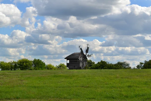 明るく青い空と雲の上の緑の野原で古い木製風車 — ストック写真