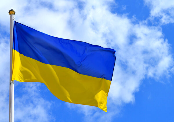 Государственный желто-синий флаг Украины над небом и облаками
