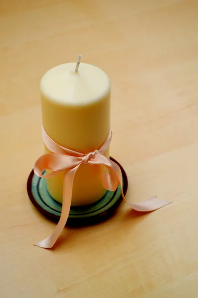 Unbenutzte große weiße Kerze mit heller Schleife auf kleinem Teller — Stockfoto