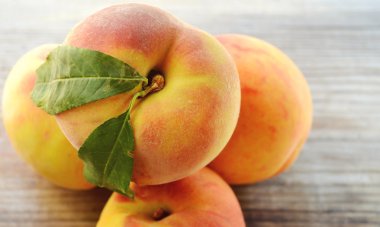 ahşap bir masa üzerinde yeşil yaprakları ile sağlıklı ve lezzetli şeftali