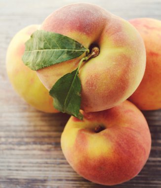 ahşap bir masa üzerinde yeşil yaprakları ile sağlıklı ve lezzetli şeftali